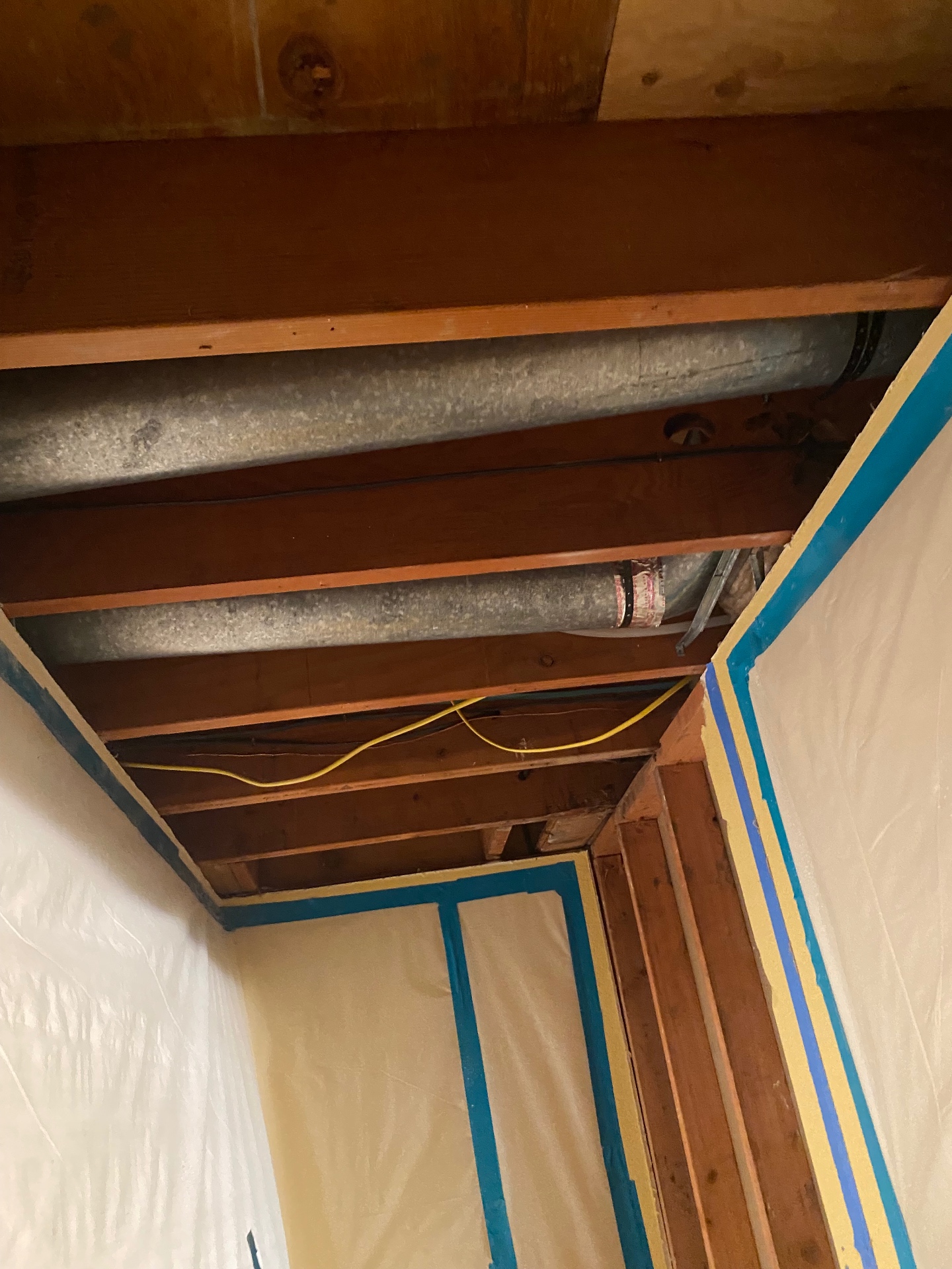 Sealed poly containment surrounding an open ceiling cavity with exposed ductwork on a Prime Environmental Solutions abatement project